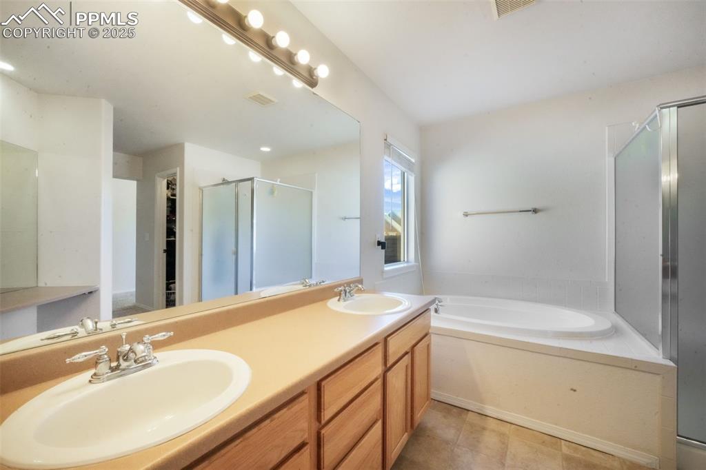Full bathroom with a garden tub, double vanity, a shower stall, and light tile patterned floors
