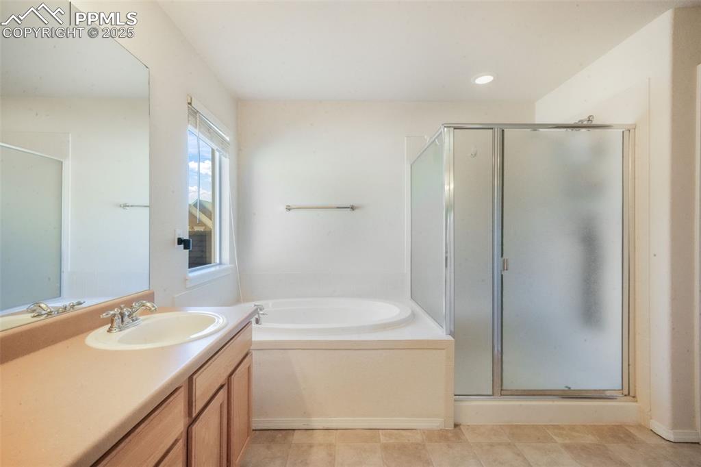 Full bath featuring a garden tub, vanity, and a stall shower