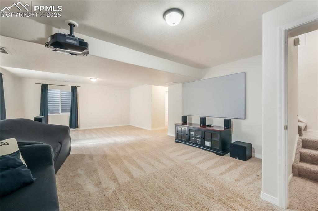Carpeted cinema with baseboards and a textured ceiling
