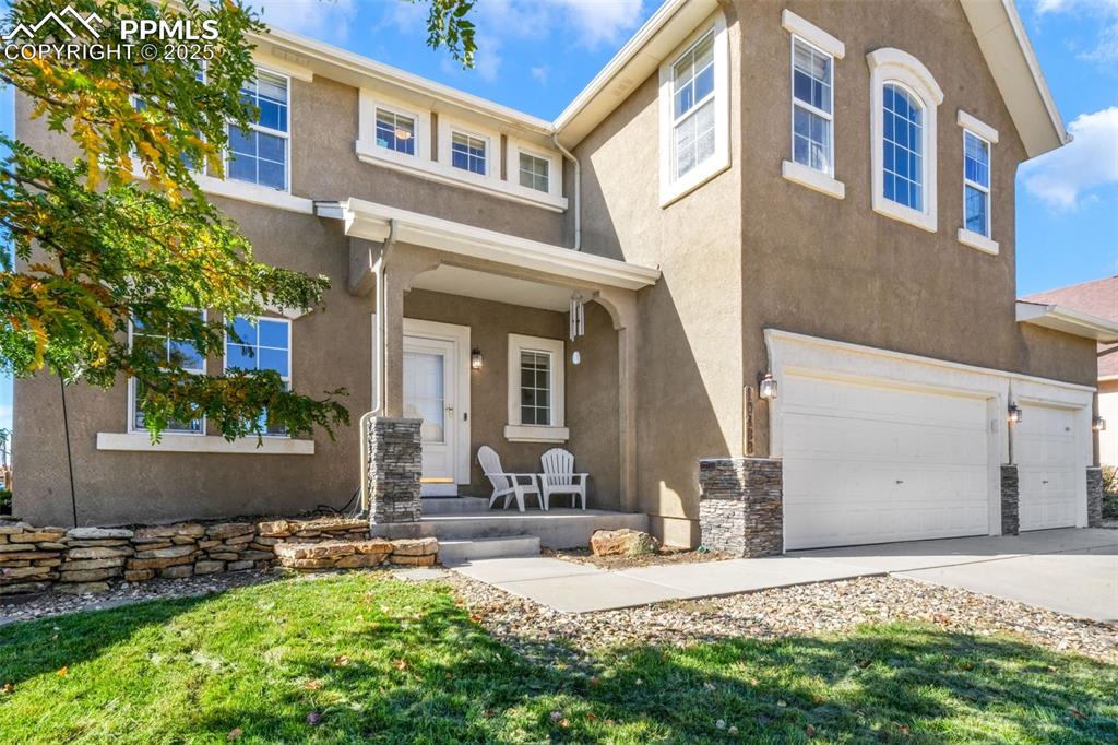 View of front facade featuring a porch, stucco siding, an attached garage, and concrete driveway