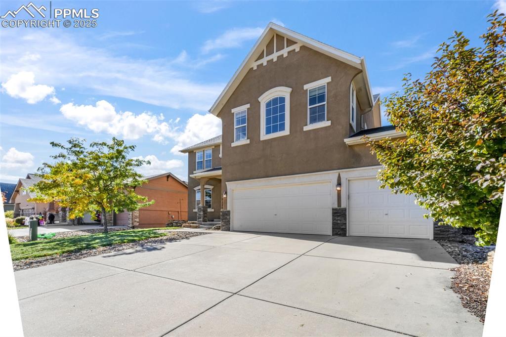 View of front of house featuring stucco siding, stone siding, a garage, and concrete driveway
