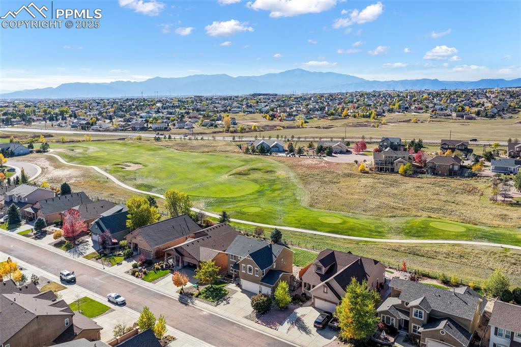 Aerial view of residential area featuring a golf course and a mountainous background