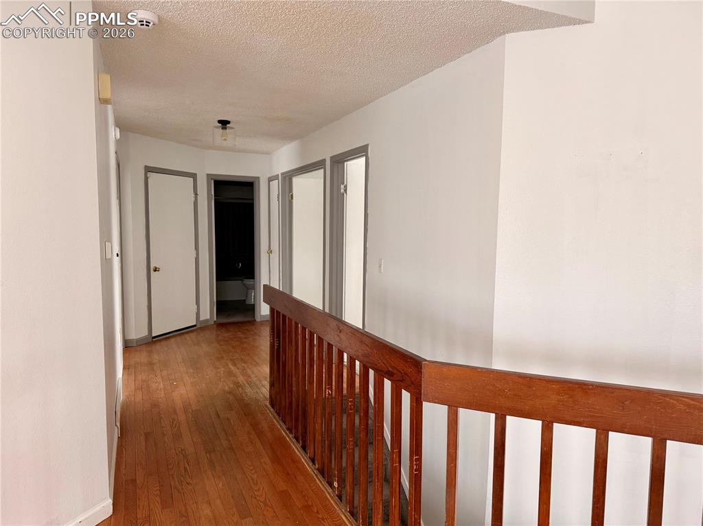 Hall featuring hardwood / wood-style flooring, an upstairs landing, and a textured ceiling