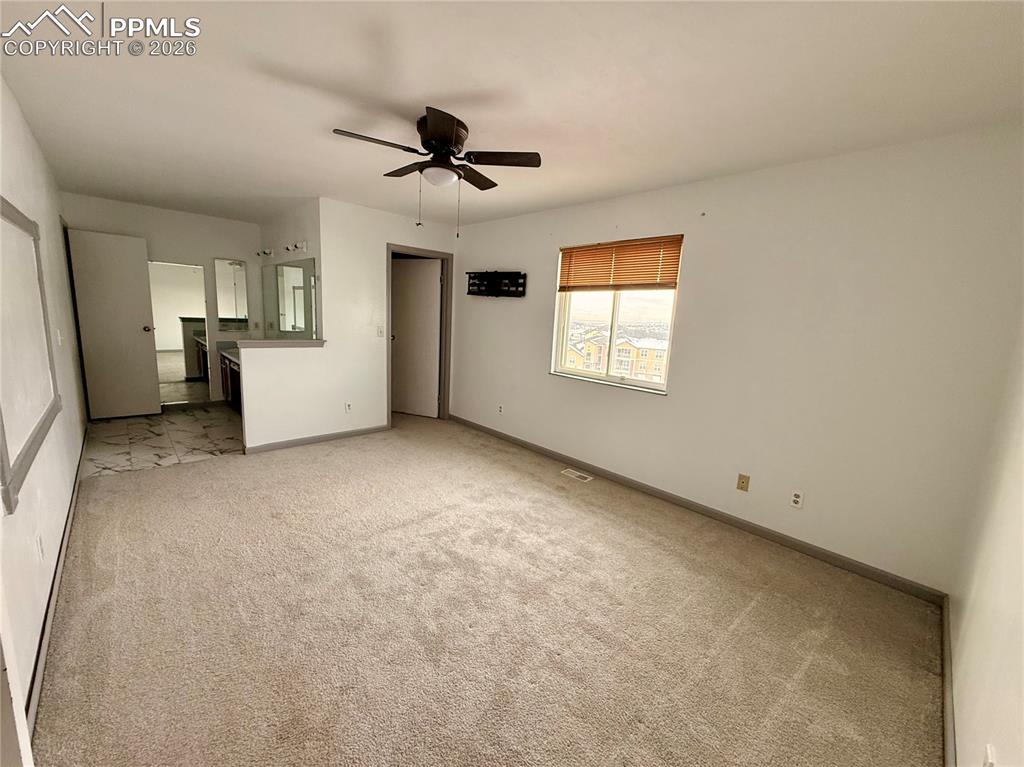 Unfurnished bedroom featuring light carpet, ceiling fan, and connected bathroom