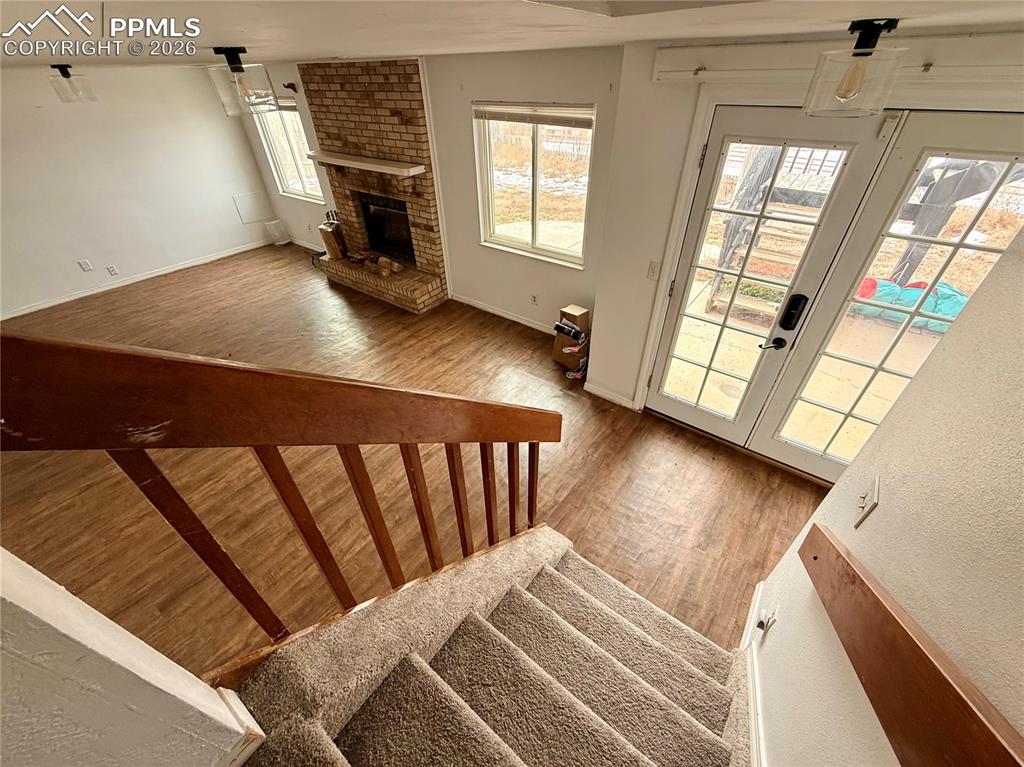 Stairway with french doors, wood finished floors, and a fireplace