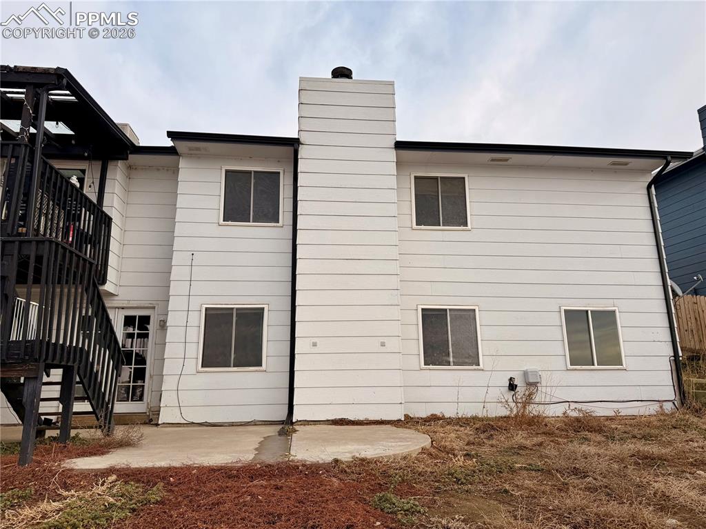 Back of house featuring a patio area, stairs, and a chimney