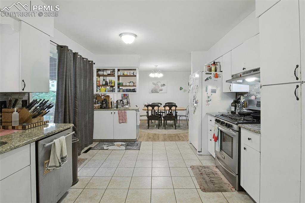 Kitchen with white cabinetry, stainless steel range with gas stovetop, light tile patterned floors, and tasteful backsplash