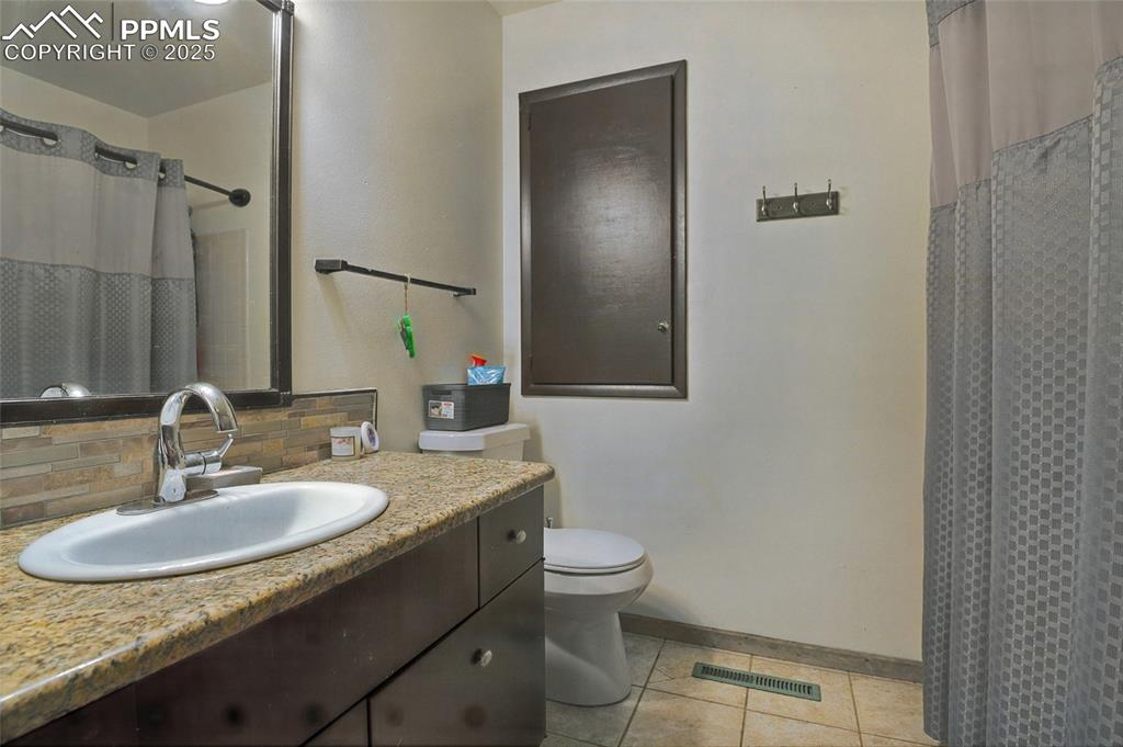 Full bathroom featuring vanity, light tile patterned flooring, decorative backsplash, and a shower with curtain