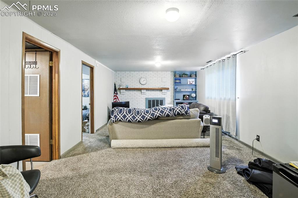 Carpeted bedroom featuring a textured ceiling and a brick fireplace