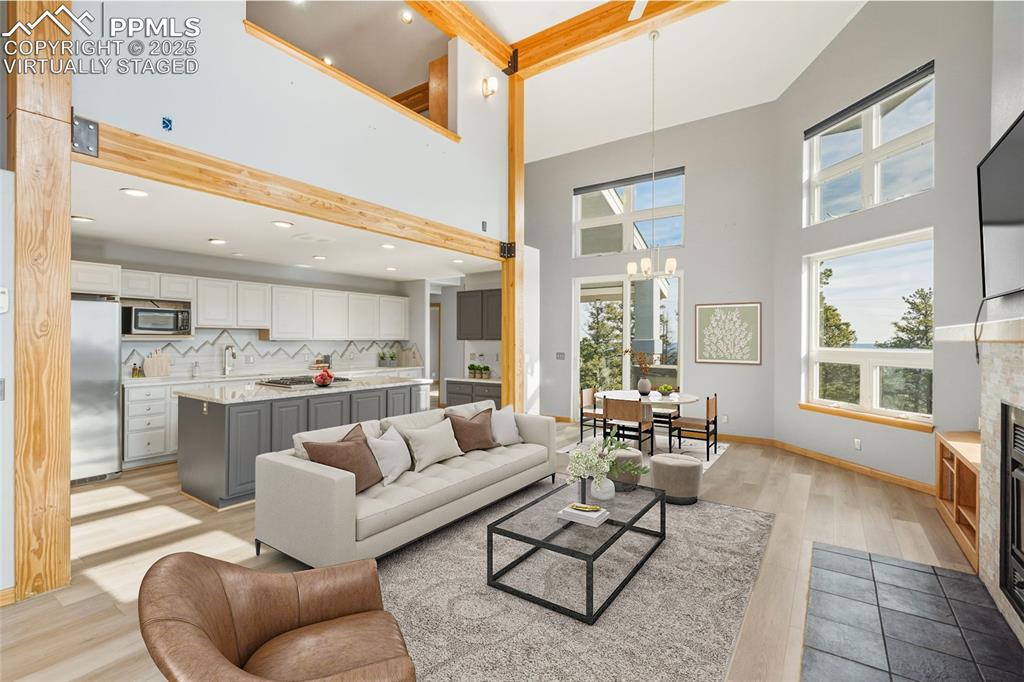 Virtually Staged - Living area featuring a glass covered fireplace, light wood-style floors, a chandelier, and recessed lighting