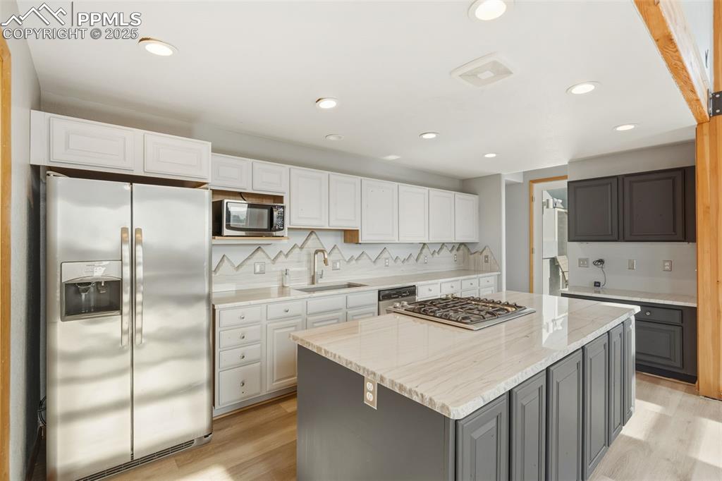 Kitchen with stainless steel appliances, decorative backsplash, light wood-style flooring, gray cabinetry, and recessed lighting