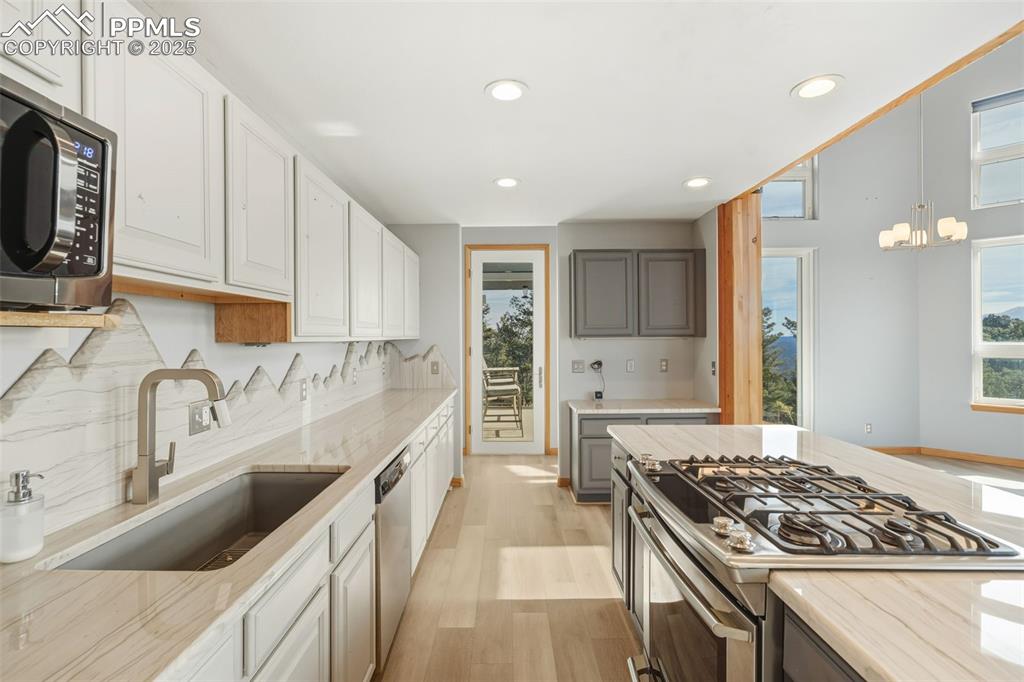 Kitchen with light wood-type flooring, appliances with stainless steel finishes, healthy amount of natural light, decorative light fixtures, and recessed lighting