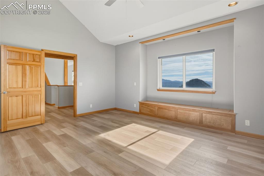 Empty room featuring light wood finished floors, ceiling fan, high vaulted ceiling, and recessed lighting