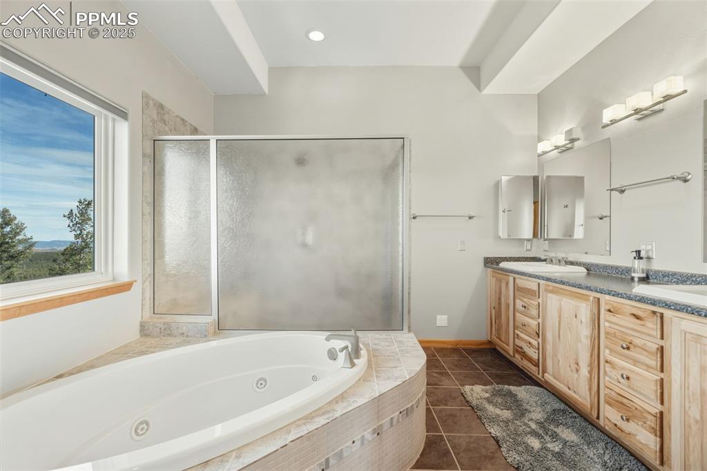 Full bath with a tub with jets, double vanity, dark tile patterned flooring, a stall shower, and recessed lighting