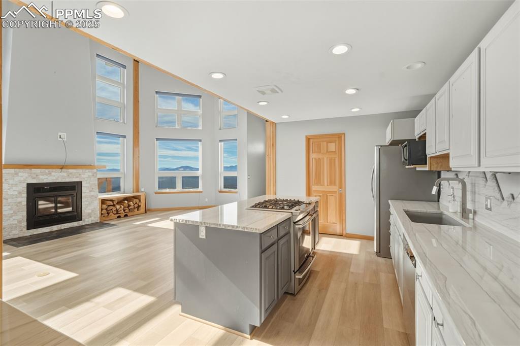 Kitchen featuring white cabinetry, light stone counters, recessed lighting, appliances with stainless steel finishes, and light wood finished floors