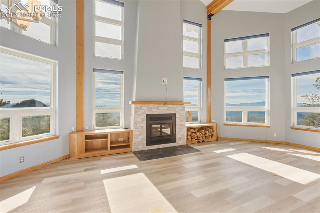 Unfurnished living room featuring a fireplace with flush hearth, wood finished floors, and a high ceiling