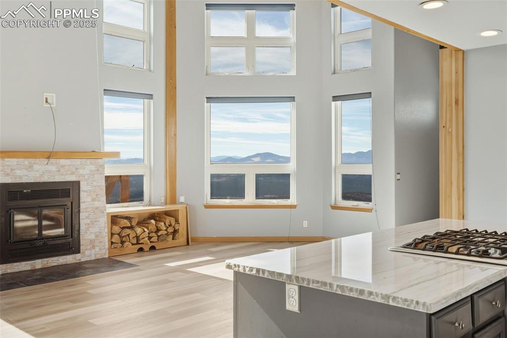 Kitchen featuring light wood-style flooring, recessed lighting, light stone counters, a glass covered fireplace, and a kitchen island