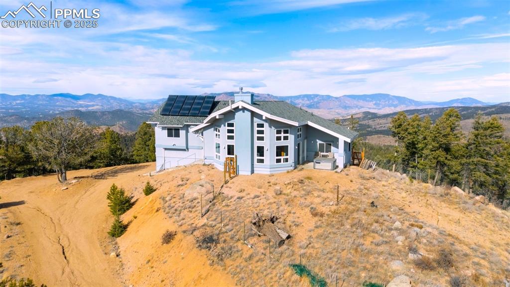 View of front of home featuring a mountain view, stucco siding, and roof mounted solar panels