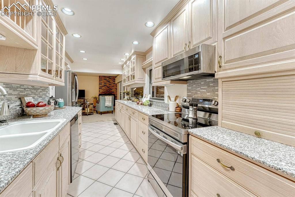 Attractive wood cabinets, some with glass fronts, granite countertops, and tile backsplash.