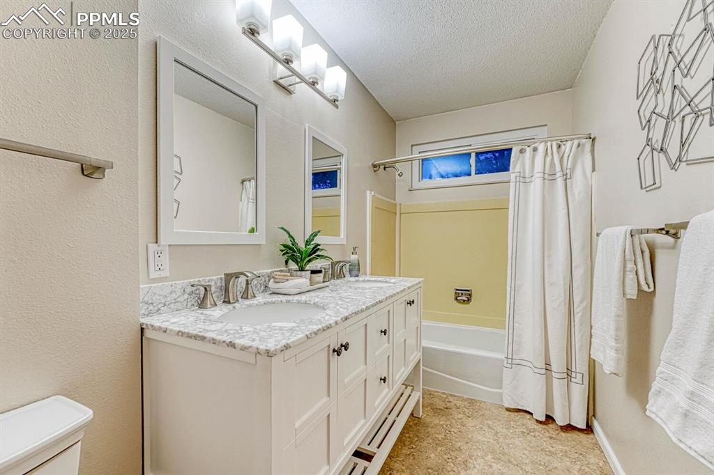 Updated Full Bathroom with dual sink vanity, framed mirrors, and tiled tub/shower.