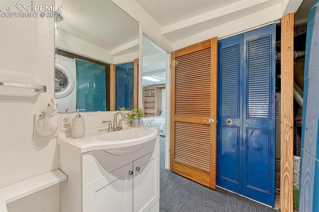 The Basement Shower Bathroom has a vanity, mirror, shower, and laundry area with stackable washer and dryer that stays.