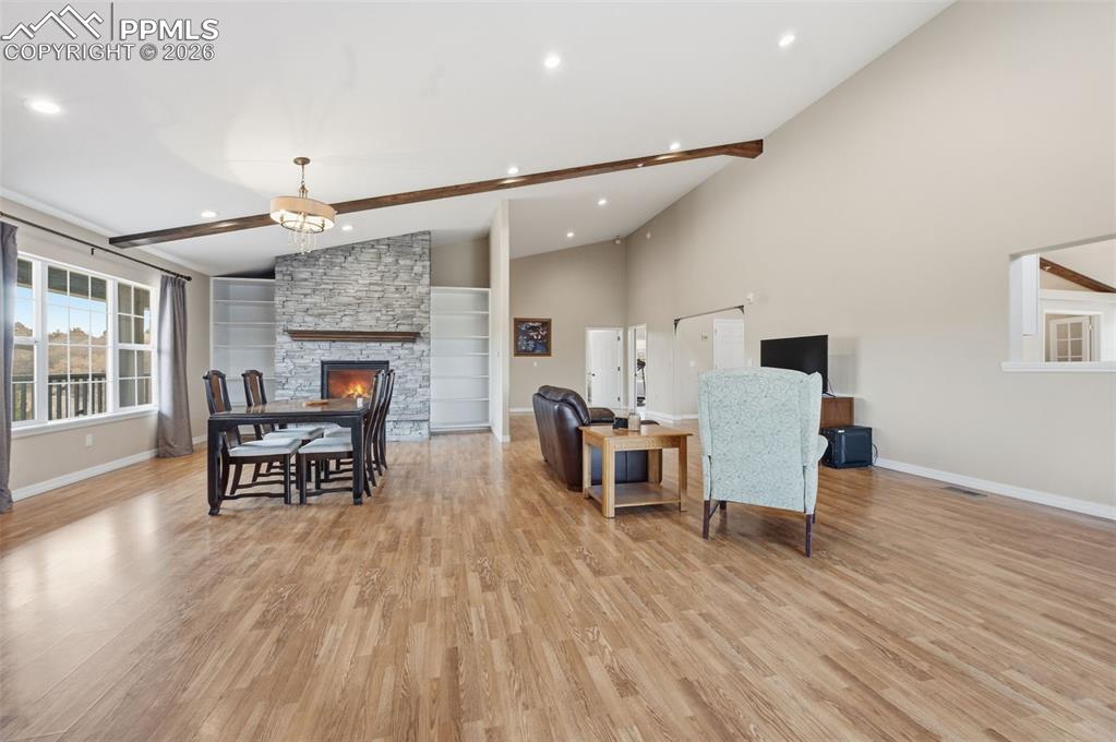 Great room with a stone fireplace and builtins. On the right is a large dining area with a pass through to the kitchen