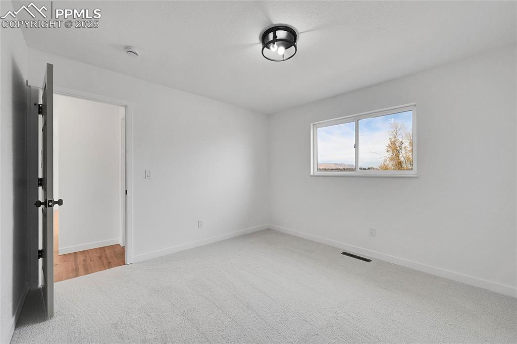 Unfurnished room featuring light carpet and baseboards
