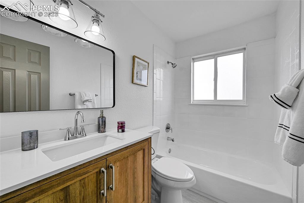 Full bath featuring shower / washtub combination, vanity, and a textured wall