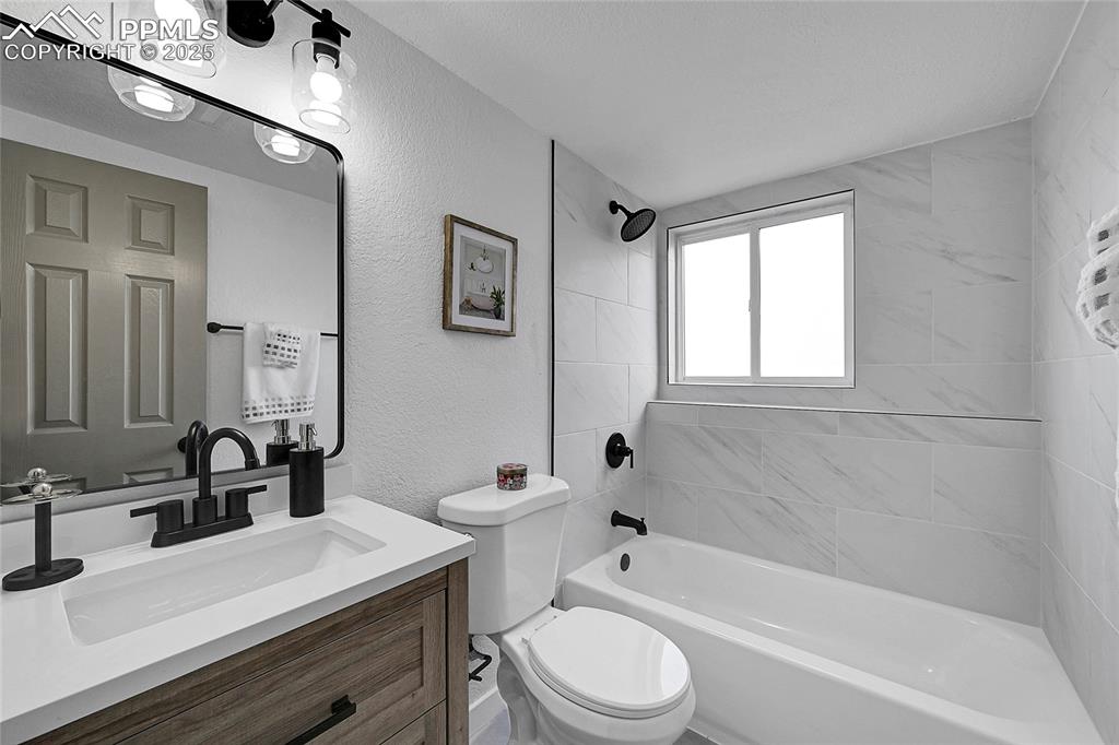 Full bath featuring a textured wall, vanity, and shower / bathtub combination
