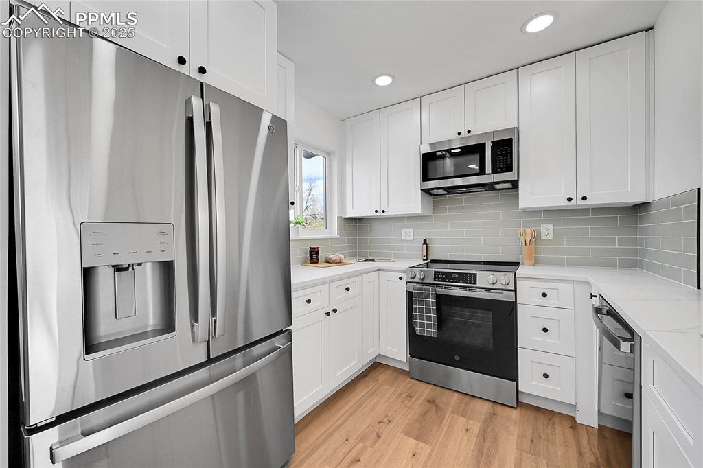 Kitchen featuring appliances with stainless steel finishes, white cabinets, and recessed lighting