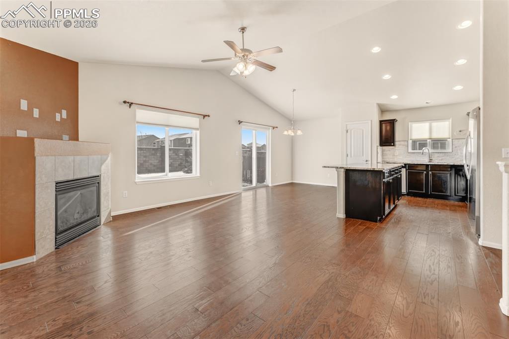 Living room with vaulted ceilings, fireplace and ceiling fan.