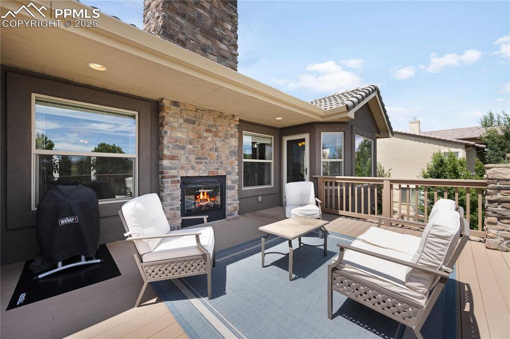 Wooden terrace with an outdoor living space with a fireplace overlooking golf course