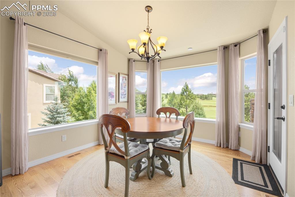 Dining area with a chandelier, light wood-style flooring, and lofted ceiling