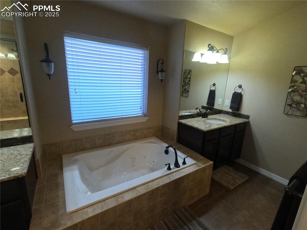 Primary  Bathroom featuring tile patterned flooring, vanity, a jetted tub, and a stall shower