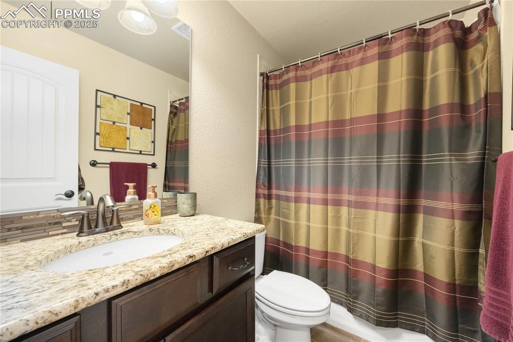 Full bath with vanity, a textured wall, and a shower with curtain