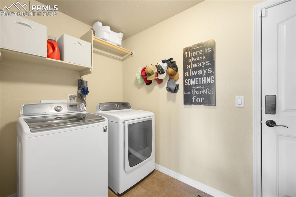 Laundry area featuring washer and dryer and light tile patterned floors