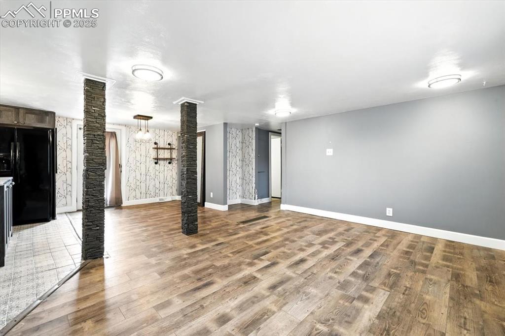 Unfurnished living room with ornate columns and wood finished floors