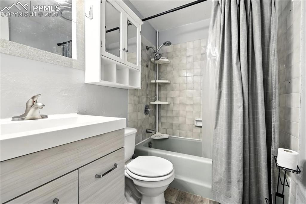 Bathroom with shower / tub combo with curtain, wood finished floors, and vanity