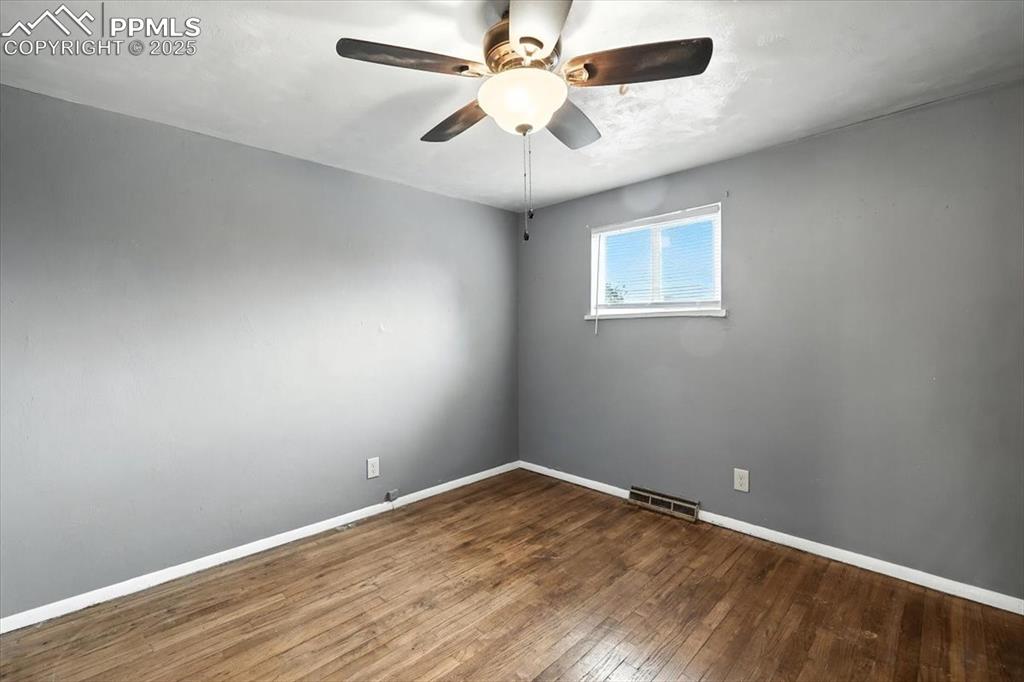 Empty room featuring hardwood / wood-style flooring and a ceiling fan