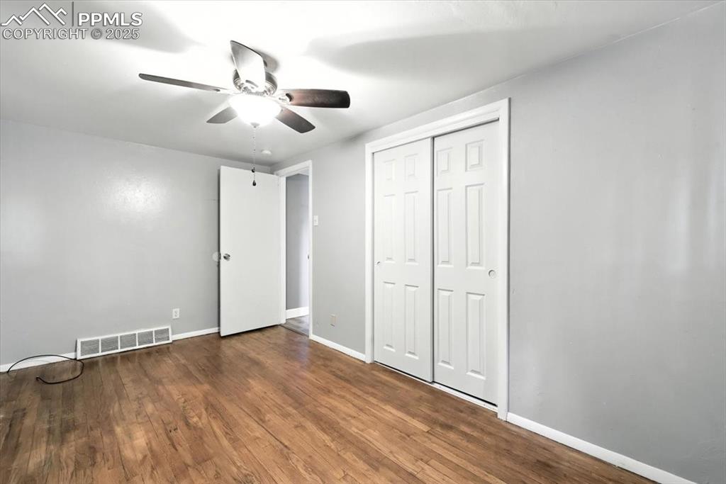 Unfurnished bedroom featuring wood finished floors, a closet, and ceiling fan