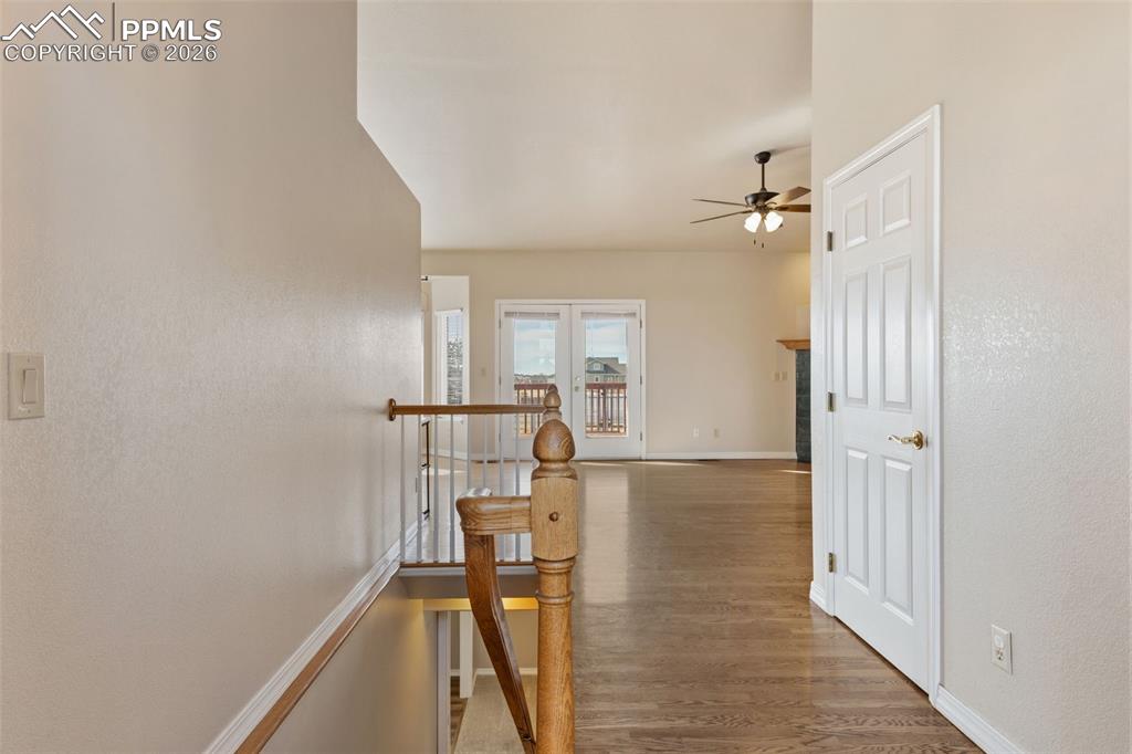 Corridor featuring an upstairs landing, light wood-style flooring, french doors, and a textured wall
