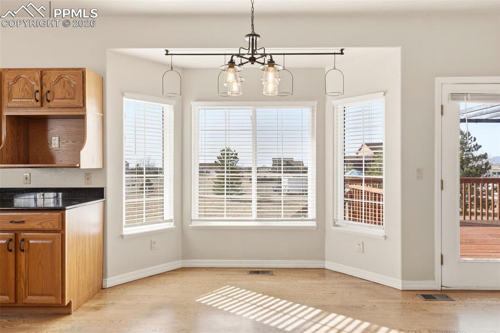 Unfurnished dining area with hanging lights and light wood-style flooring