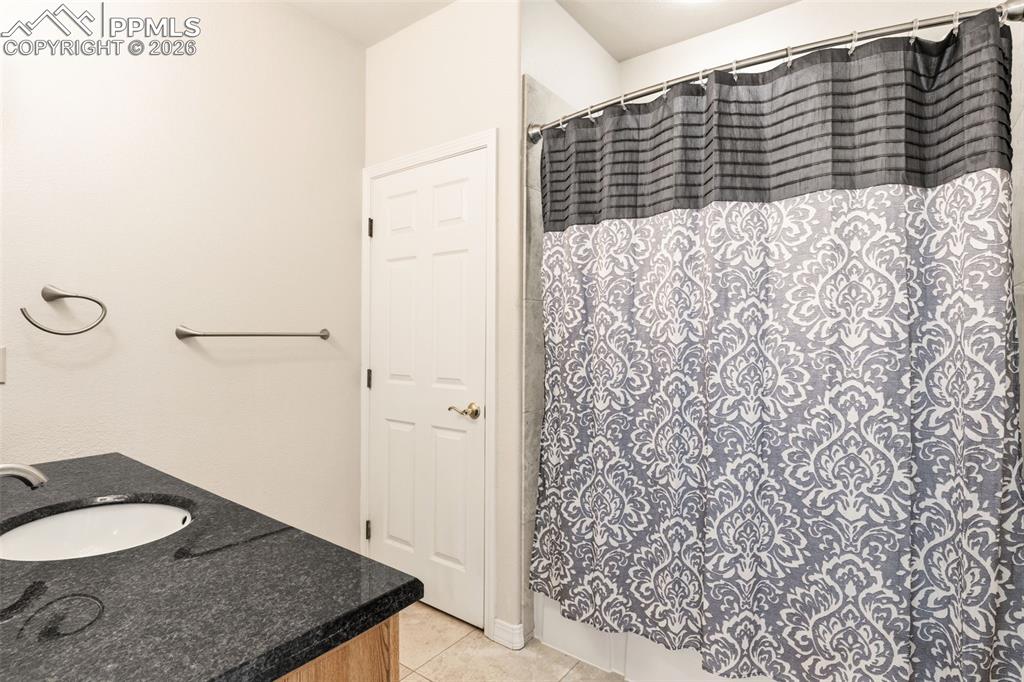 Full bath featuring vanity, curtained shower, and light tile patterned floors