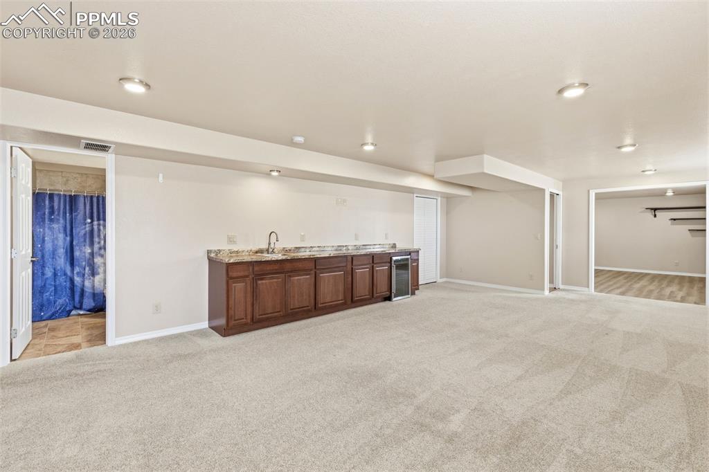 Indoor wet bar featuring light colored carpet and wine cooler