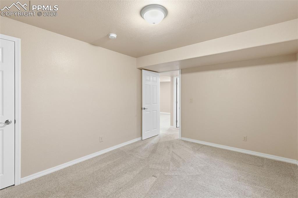 Empty room with light carpet and a textured ceiling