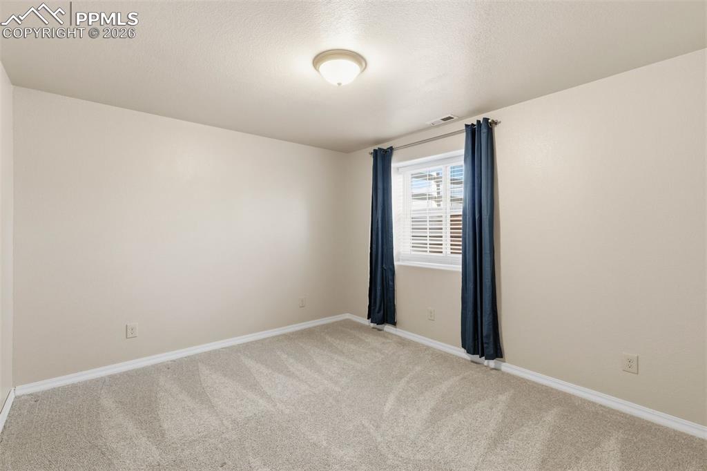 Empty room featuring light colored carpet and a textured ceiling