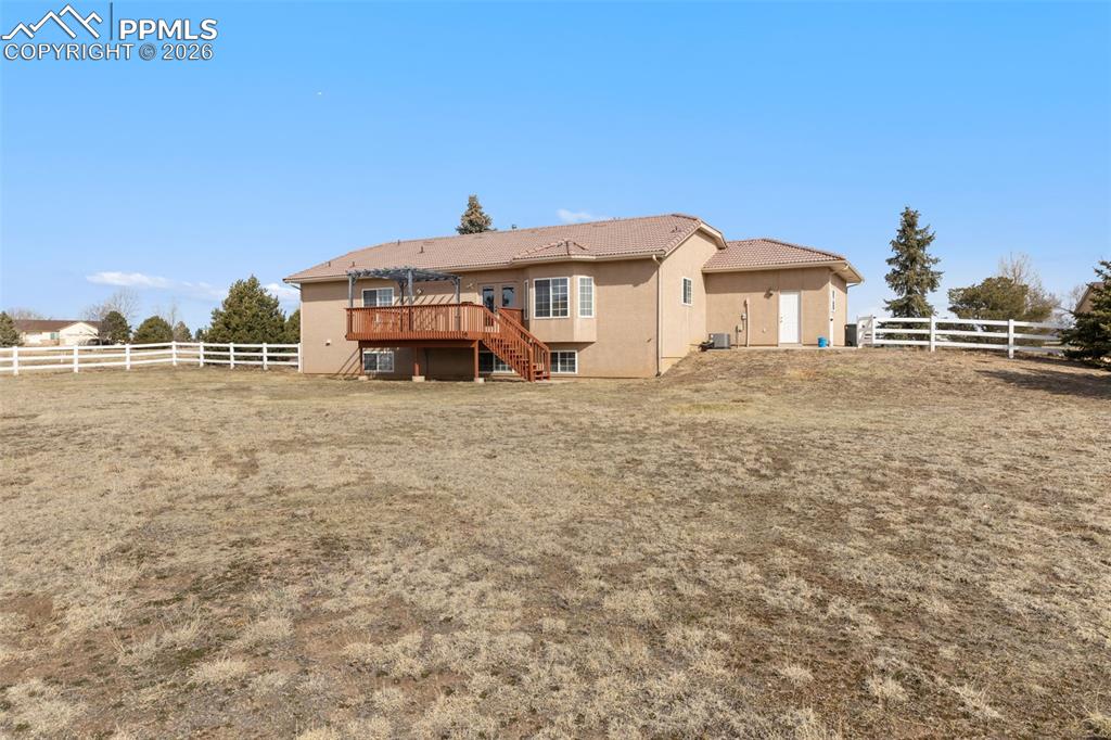 Back of house featuring a fenced backyard, a deck, and stucco siding