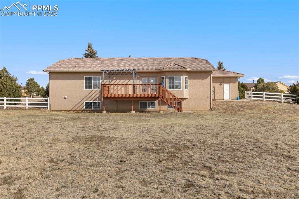Back of house featuring a fenced backyard, a deck, a tile roof, and stucco siding