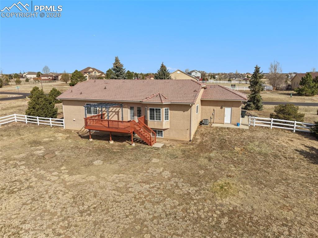 Rear view of house with a fenced backyard, stucco siding, a tiled roof, and a deck