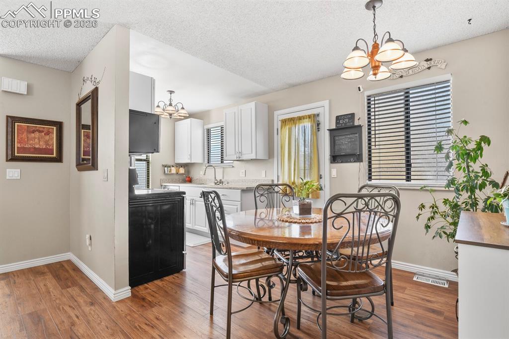 Dining room with suspended lighting, a textured ceiling, and dark wood-type flooring